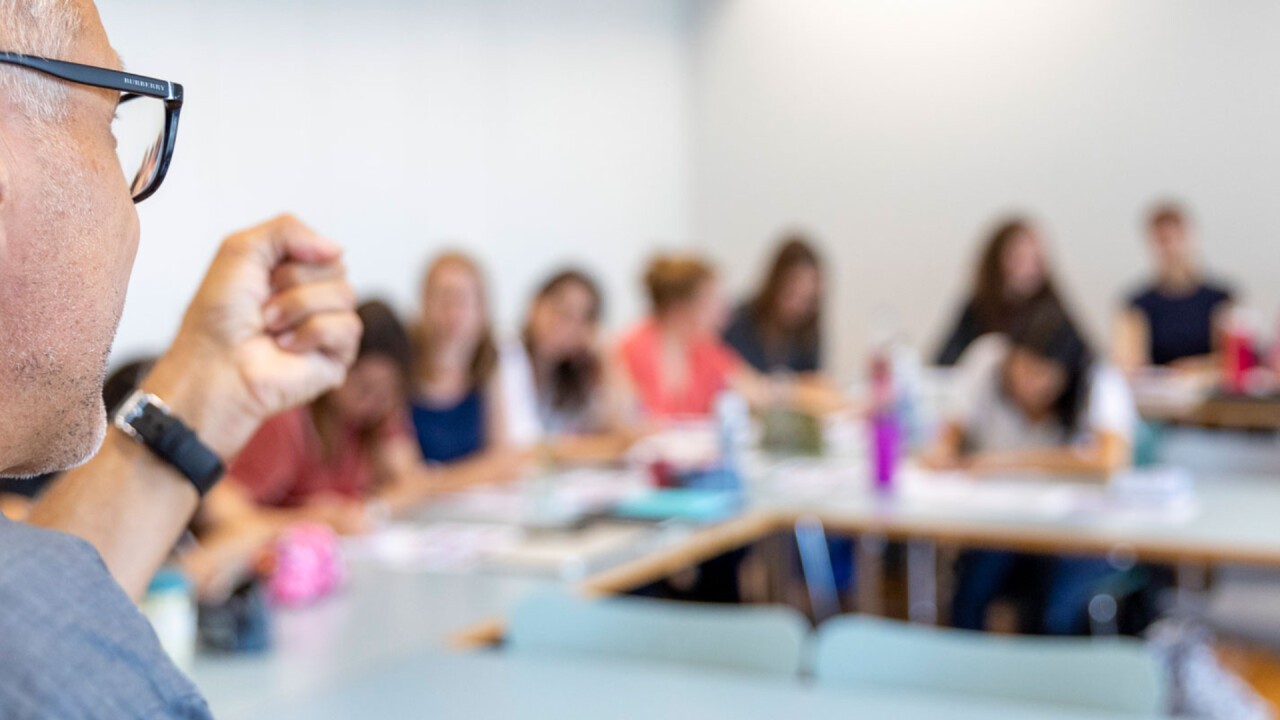 Ein Dozent erklärt mehreren Studierenden etwas. 