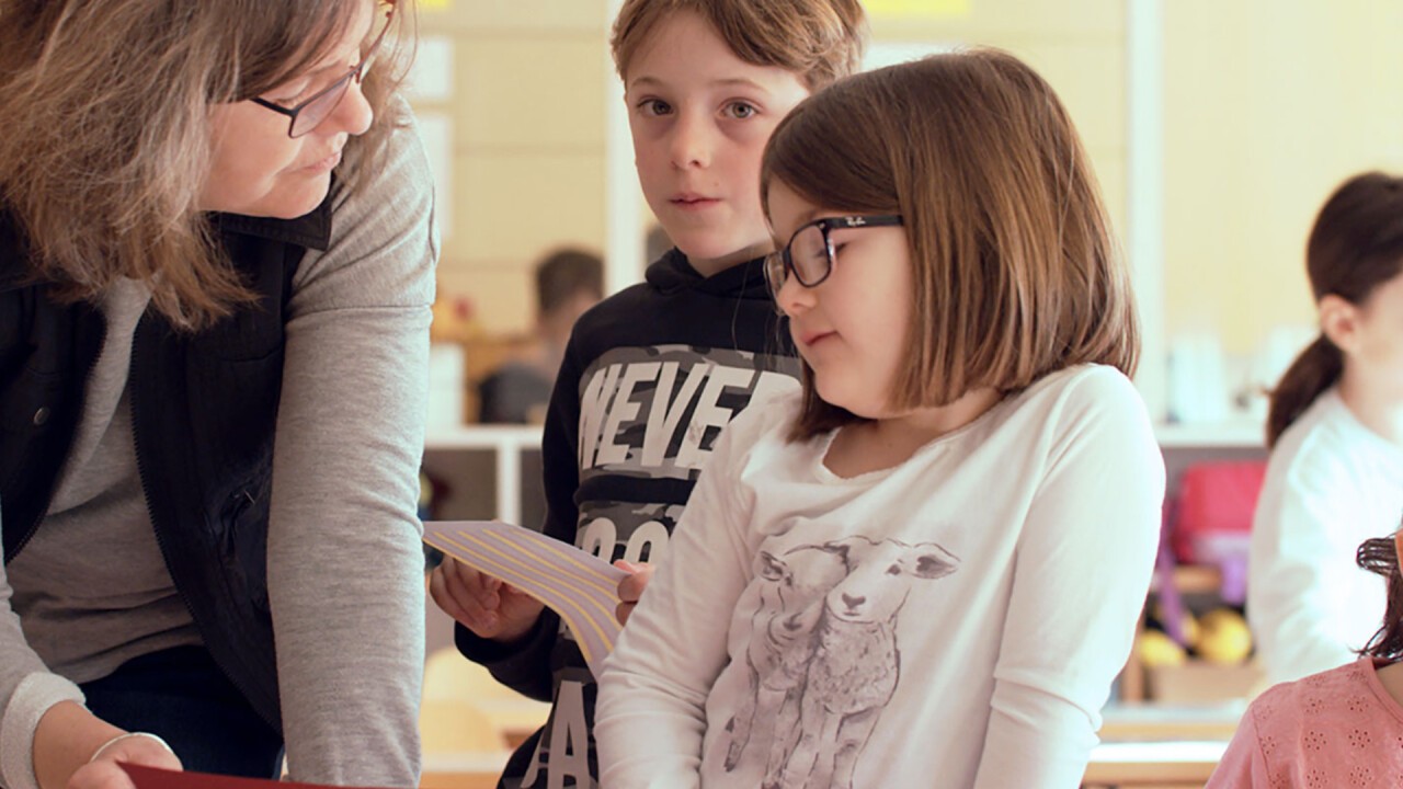 Schülerin und Schüler unterhalten sich mit einer Lehrerin.