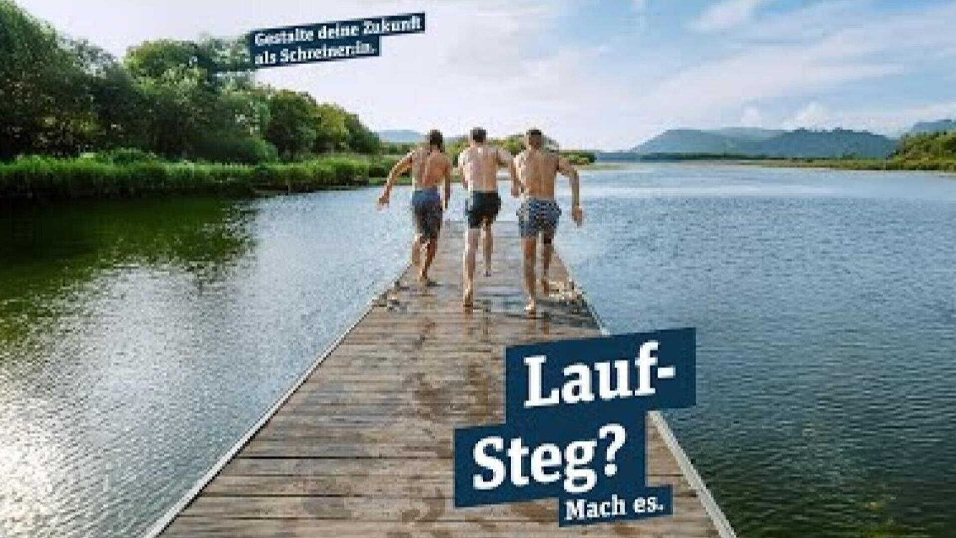 Vier Personen in Badeanzügen laufen auf einem hölzernen Steg in Richtung eines Sees, umgeben von Grün und Bergen. Der deutsche Text lautet: "Gestalte deine Zukunft als Schreiner:in. Laufsteg? Mach es.".