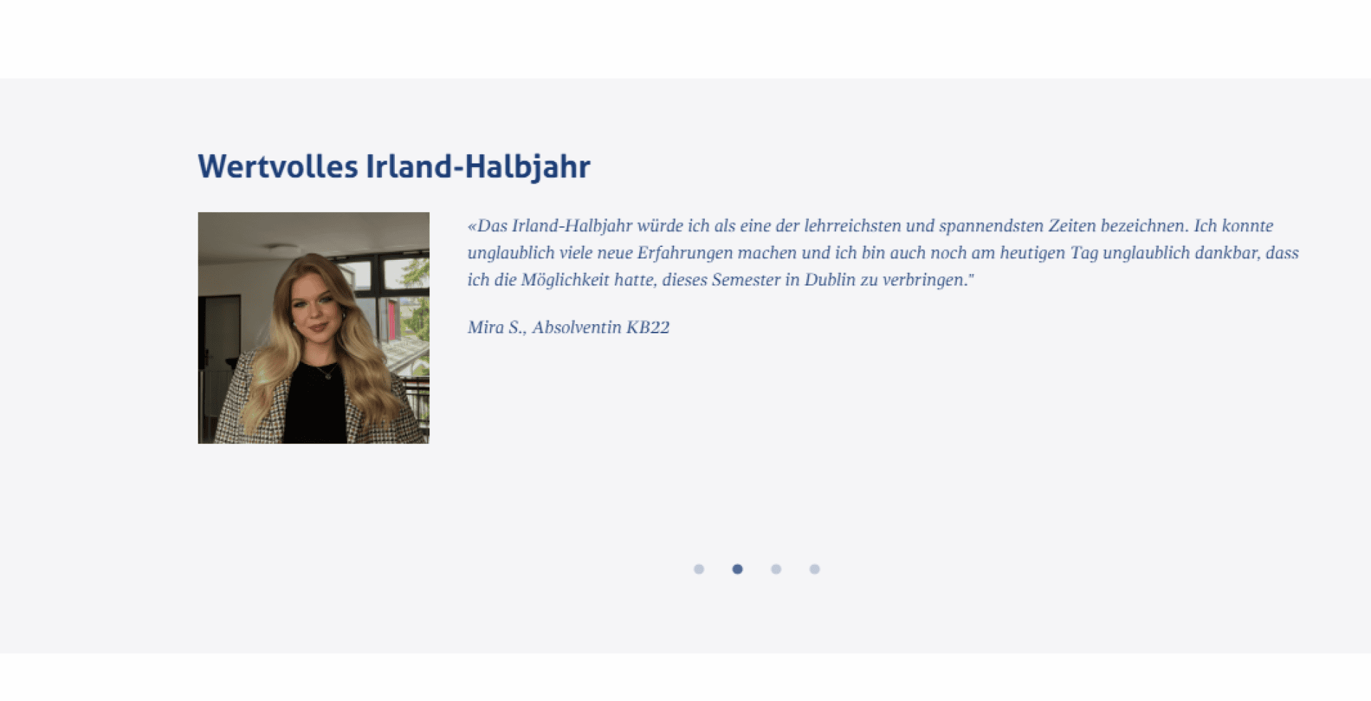 Eine junge Frau mit langen blonden Haaren, die einen schwarz-weiß karierten Blazer trägt, steht lächelnd in einem Innenbereich. Neben ihr steht ein deutsches Zeugnis über ihr wertvolles Semester in Irland.