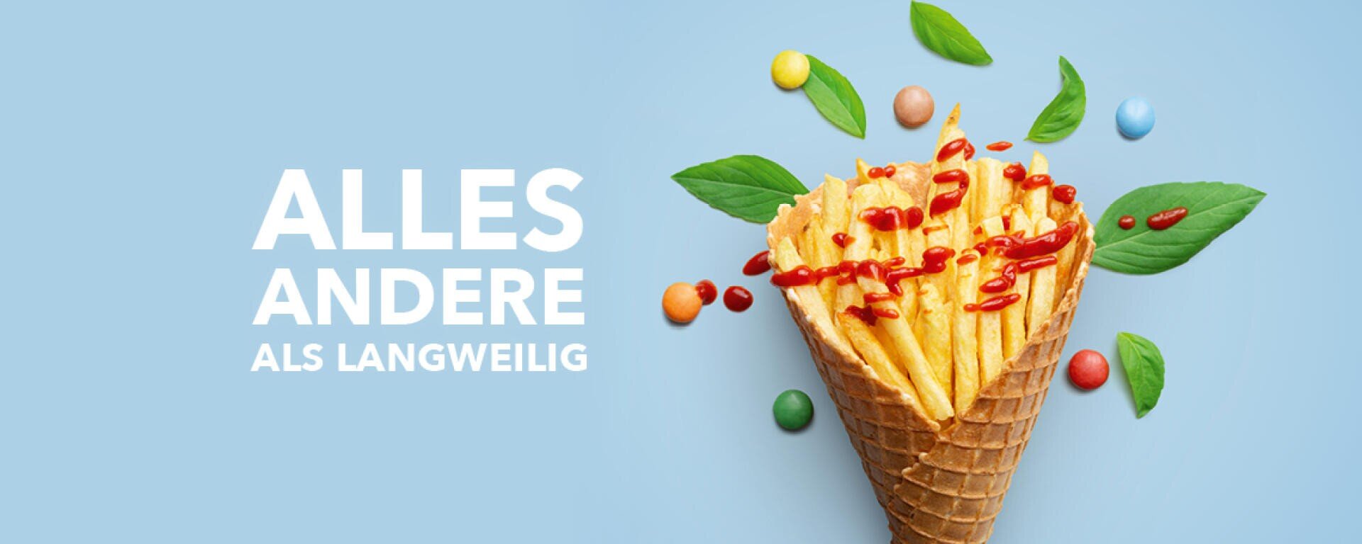 Eine Waffeleiswaffel gefüllt mit Pommes frites mit Ketchup, umgeben von grünen Blättern und bunten Bonbons auf einem hellblauen Hintergrund. Der Text auf der linken Seite lautet: ALLES ANDERE ALS LANGWEILIG.