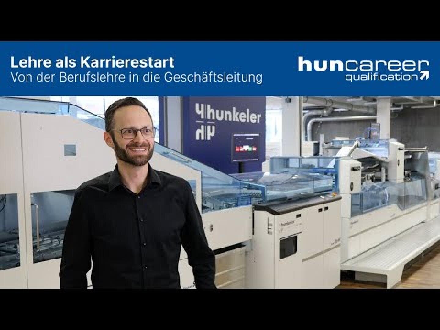 Ein Mann mit Brille und schwarzem Hemd steht lächelnd vor großen Industriemaschinen. Auf dem Transparent darüber steht: Lehre als Karrierestart - Von der Berufslehre in die Geschäftsleitung und huncareer qualification.