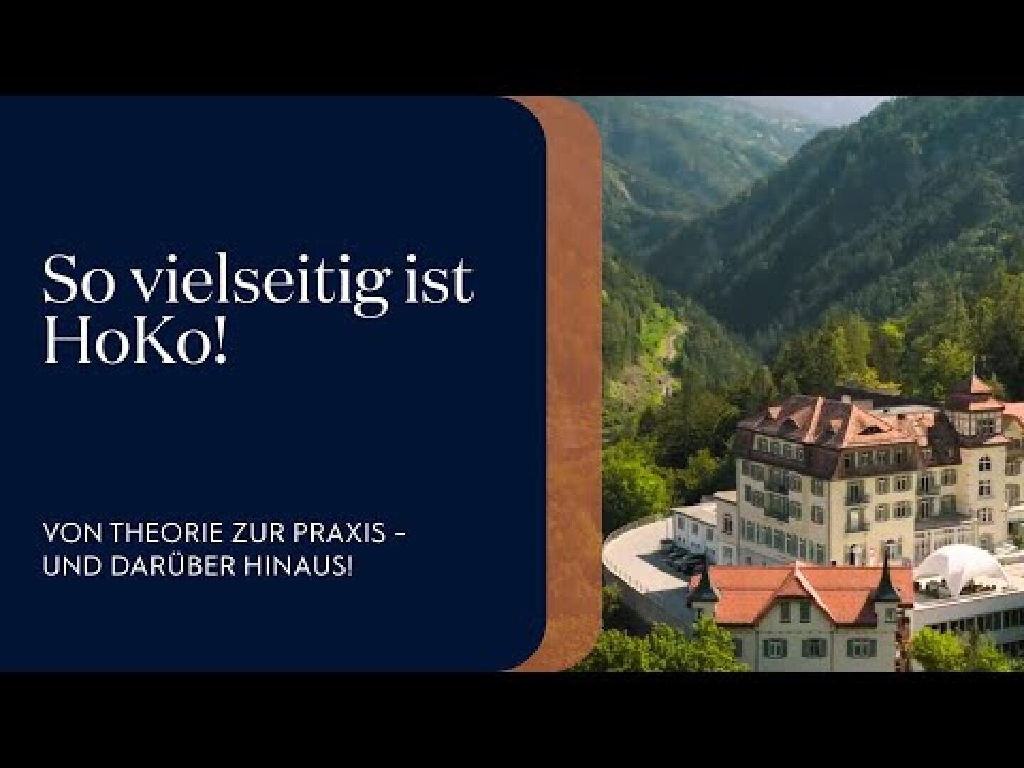Präsentationsfolie mit einem dunkelblauen Kasten auf der linken Seite, der weißen Text enthält: So vielseitig ist HoKo! Von der Theorie zur Praxis - und darüber hinaus! Rechts ist eine Luftaufnahme eines großen Gebäudes, umgeben von Bergen und Bäumen, zu sehen.