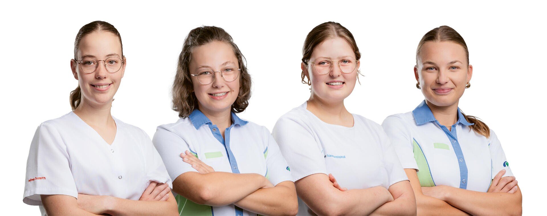 Vier junge Frauen in weißen und blauen Uniformen stehen Seite an Seite vor einem weißen Hintergrund, lächeln selbstbewusst und haben die Arme verschränkt.