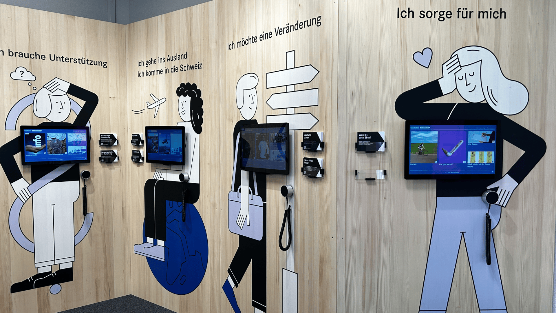Wandausstellung mit Comicfiguren, Touchscreen-Panels, Kopfhörern und deutschen Texten zu den Themen Unterstützung, Umzug ins Ausland, Veränderung und Selbstfürsorge. Jede Station bietet den Besuchern interaktive Informationen.