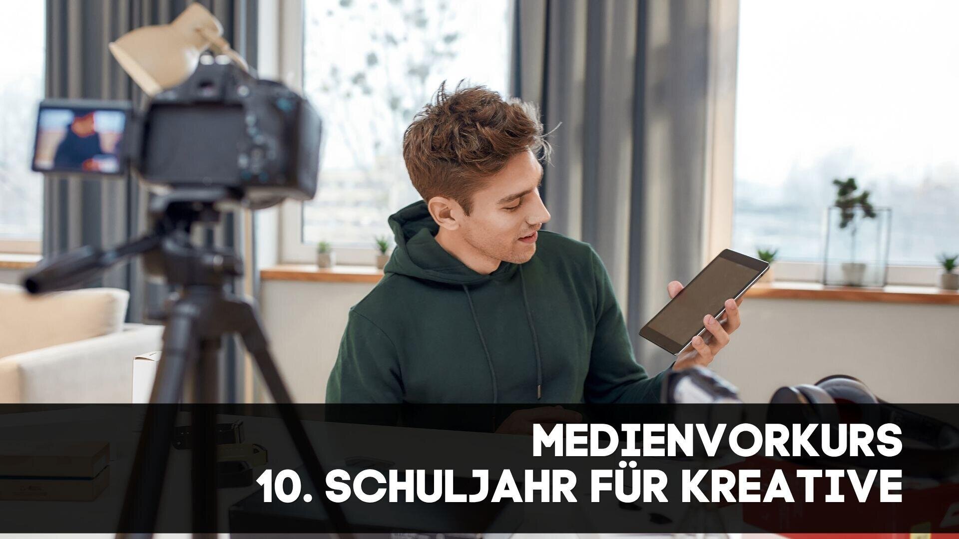 Ein Jugendlicher hält ein Tablet vor eine Kamera, die in einem hellen Raum filmt. Der Text lautet: Medienvorkurs 10. Schuljahr für Kreative...