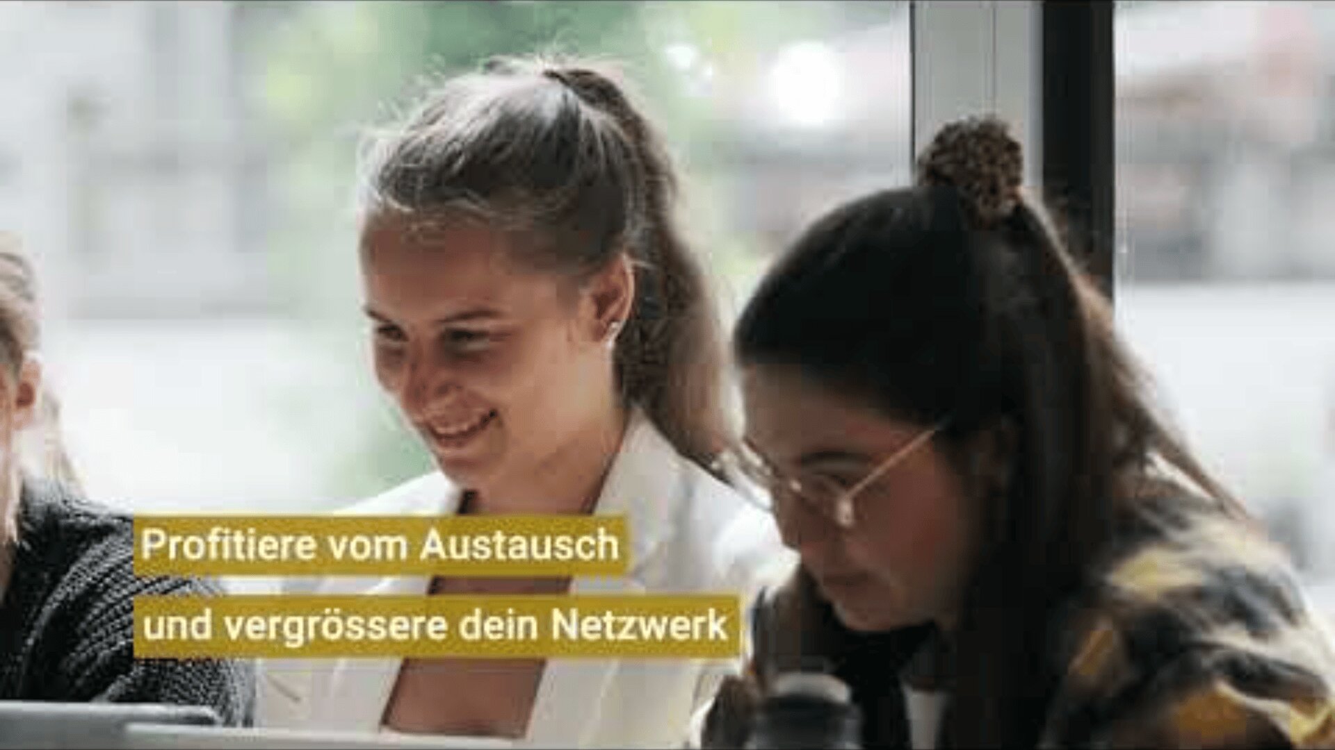 Zwei Frauen sitzen Seite an Seite in einem Haus, arbeiten zusammen und lächeln. Der deutsche Text auf dem Bild lautet: Profitiere vom Austausch und vergrössere dein Netzwerk, d.h. Profitiere vom Austausch und erweitere dein Netzwerk.