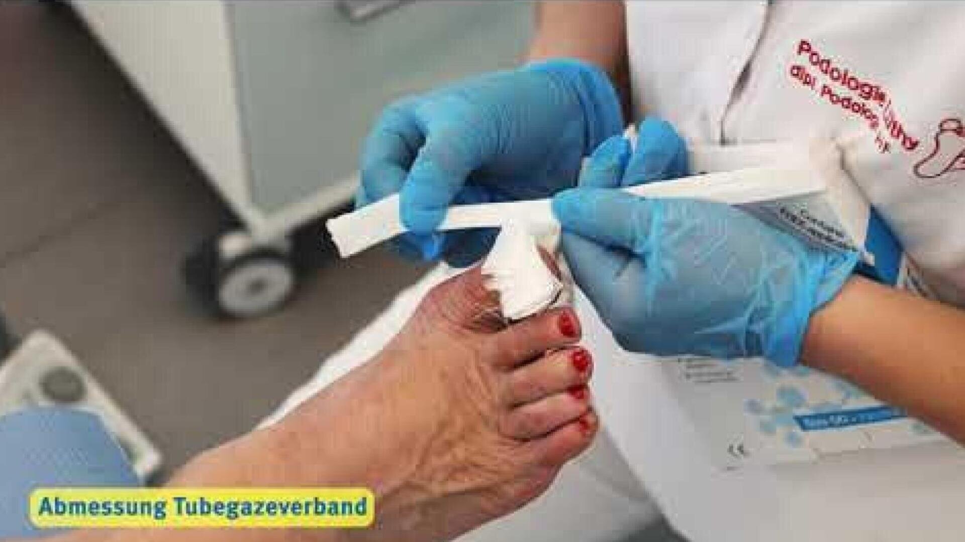 Ein Fußpfleger mit blauen Handschuhen legt einem Patienten einen Verband am Zeh an.
