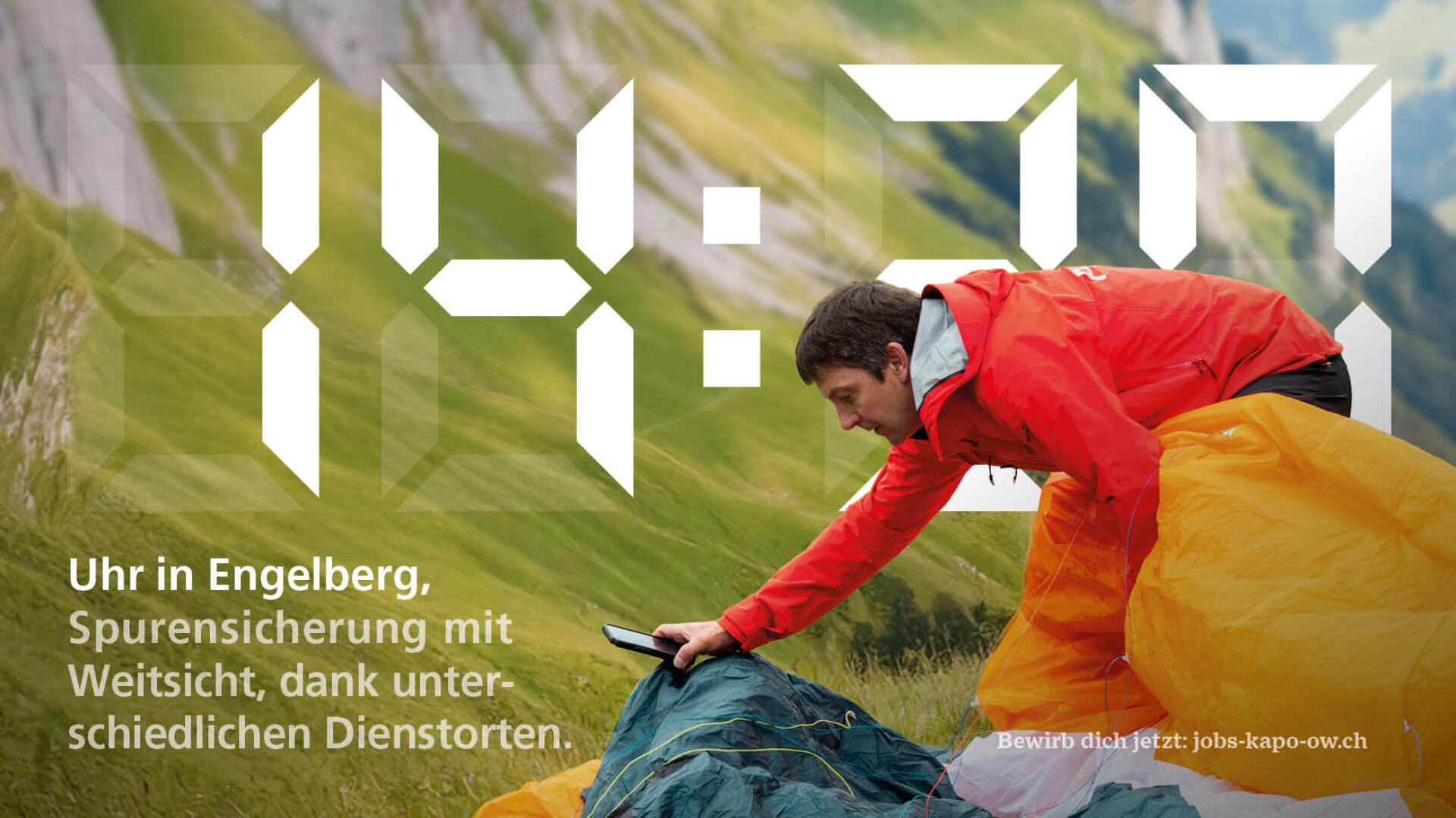 Ein Mann in einer roten Jacke prüft eine Ausrüstung an einem grasbewachsenen Berghang mit steilen Gipfeln im Hintergrund. Große digitale Zahlen 14:30 sind eingeblendet, zusammen mit einem deutschen Text über einen Job in Engelberg.