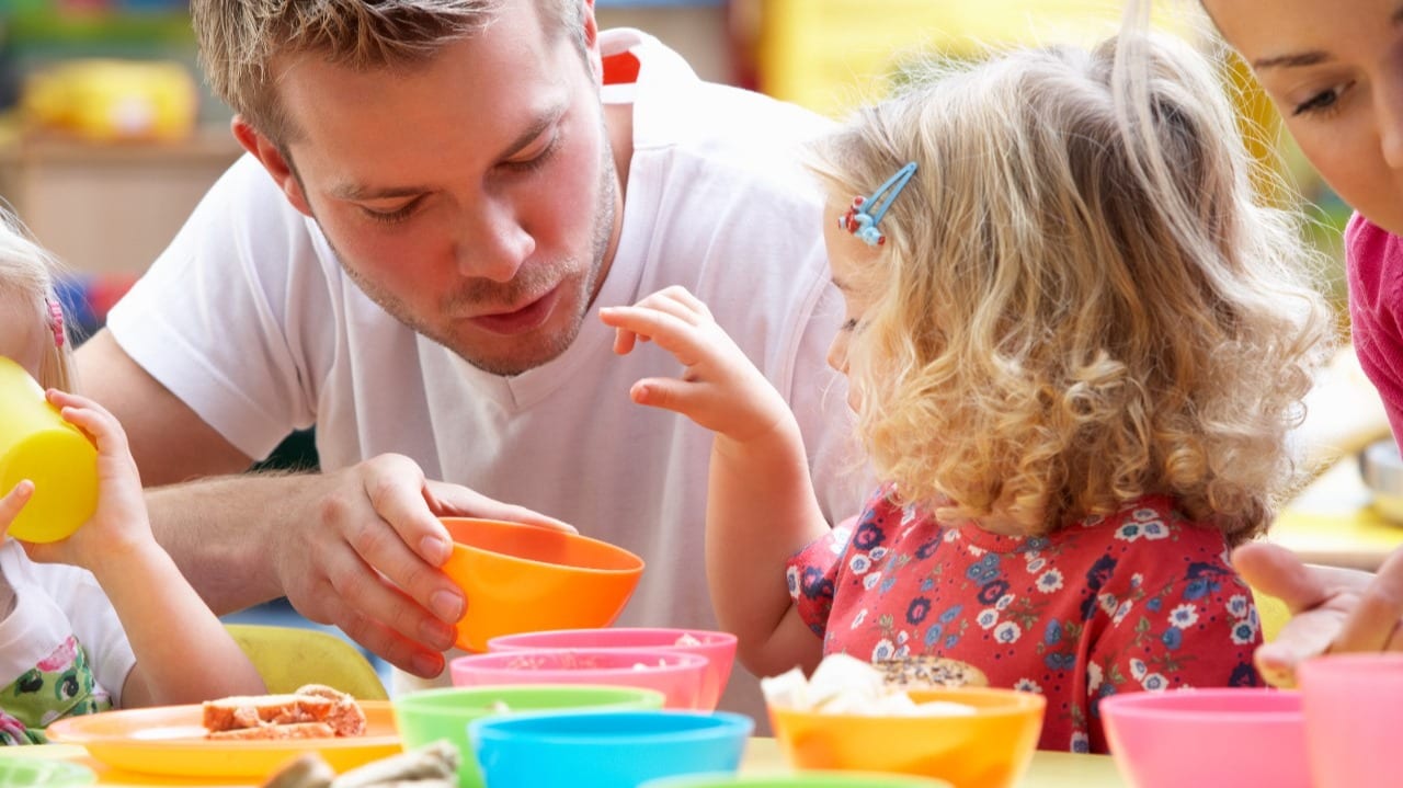 Ein Fachmann Betreuung begleitet Kinder beim Essen.